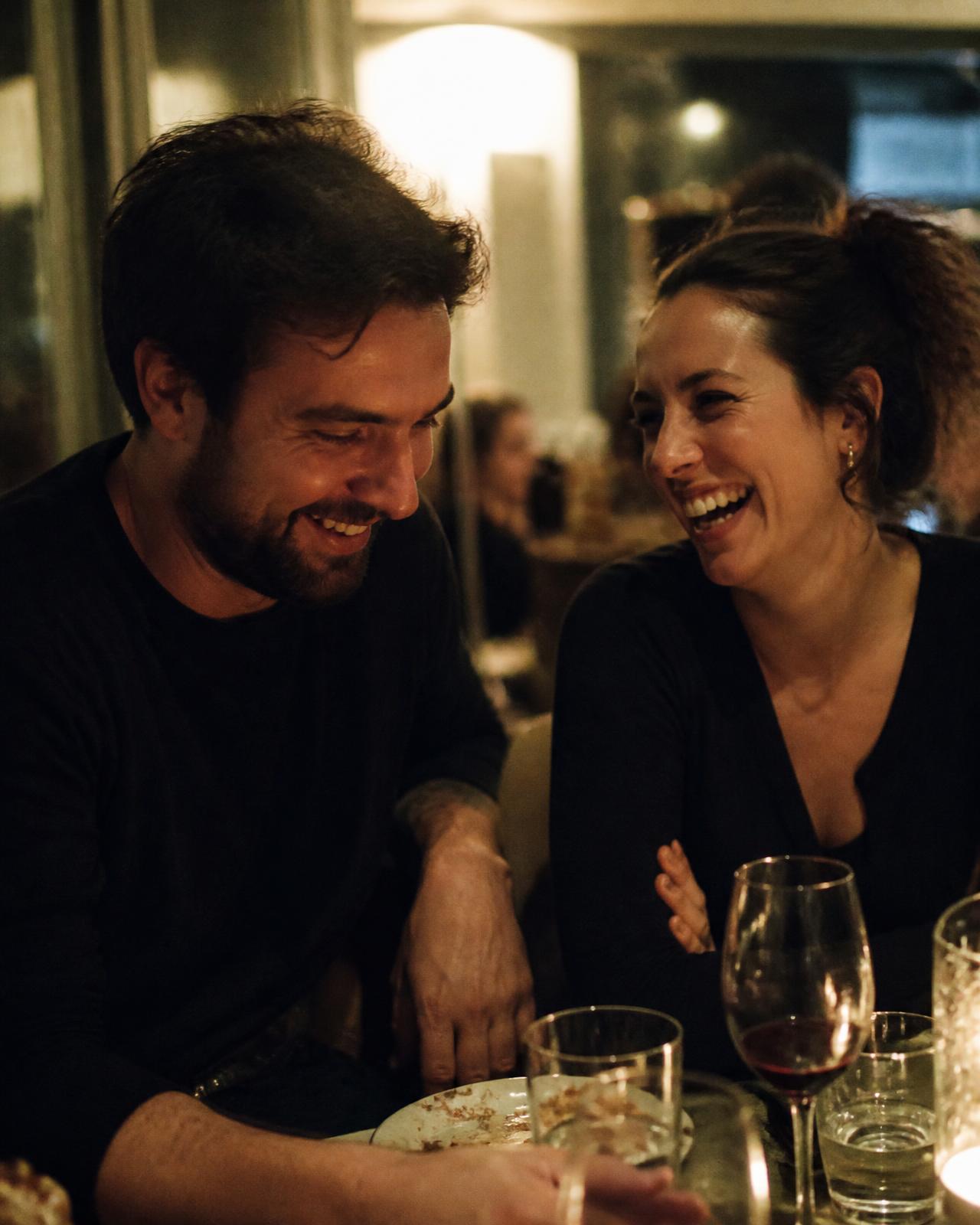 A couple laughing over dinner at a small restaurant